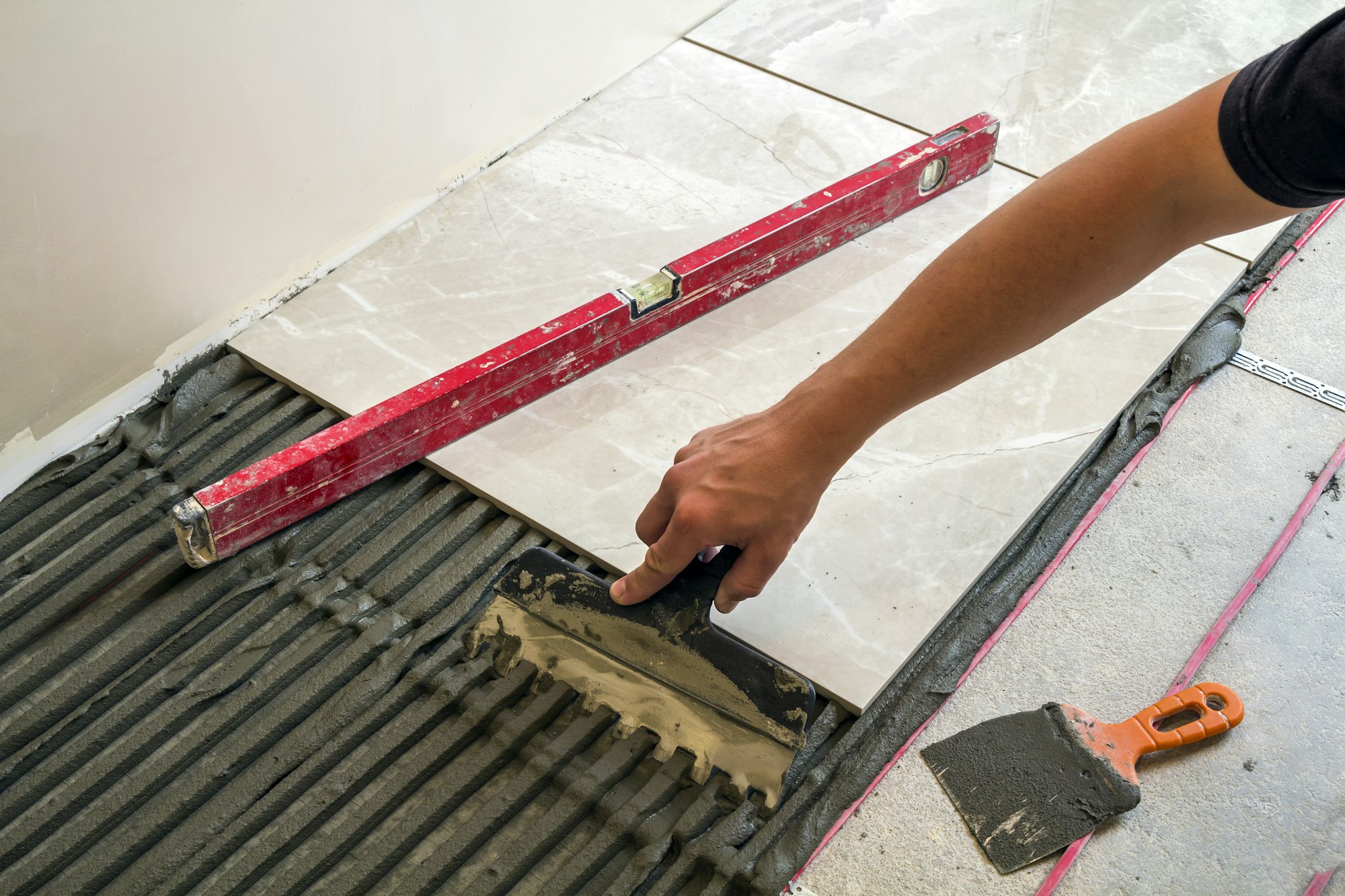 Ceramic tiles and tools for tiler. Worker hand installing floor tiles. Home improvement, renovation