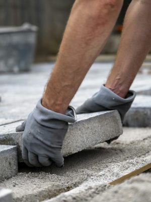 DIY project - male hands paving outdoor patio with cement tiles